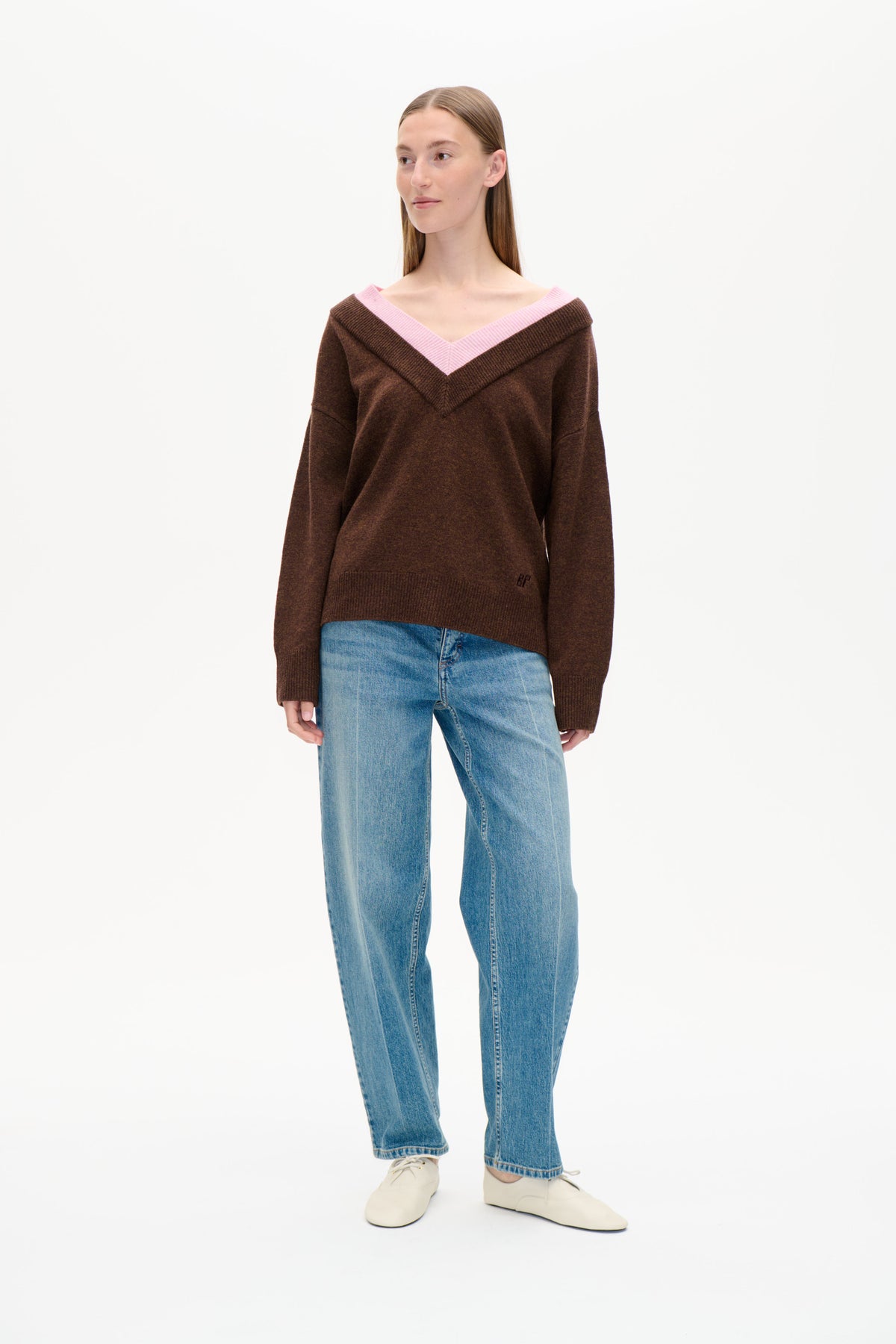 Set forfra: brun strikket sweater med bred lyserød v-hals, stylet med lyseblå jeans.