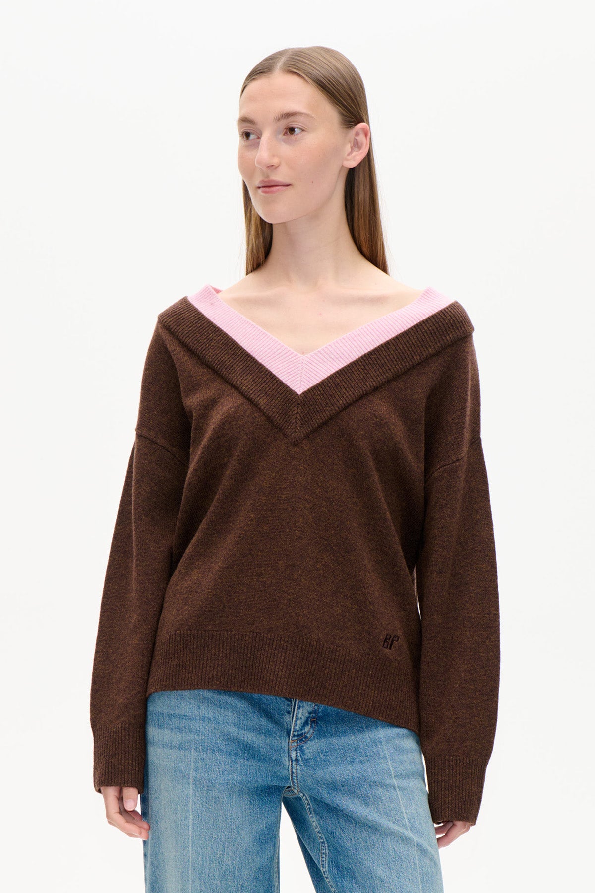 Set forfra: mørkebrun Sweater med bred, skulderfri V-hals med pink ribkant, stylet med blå jeans.
