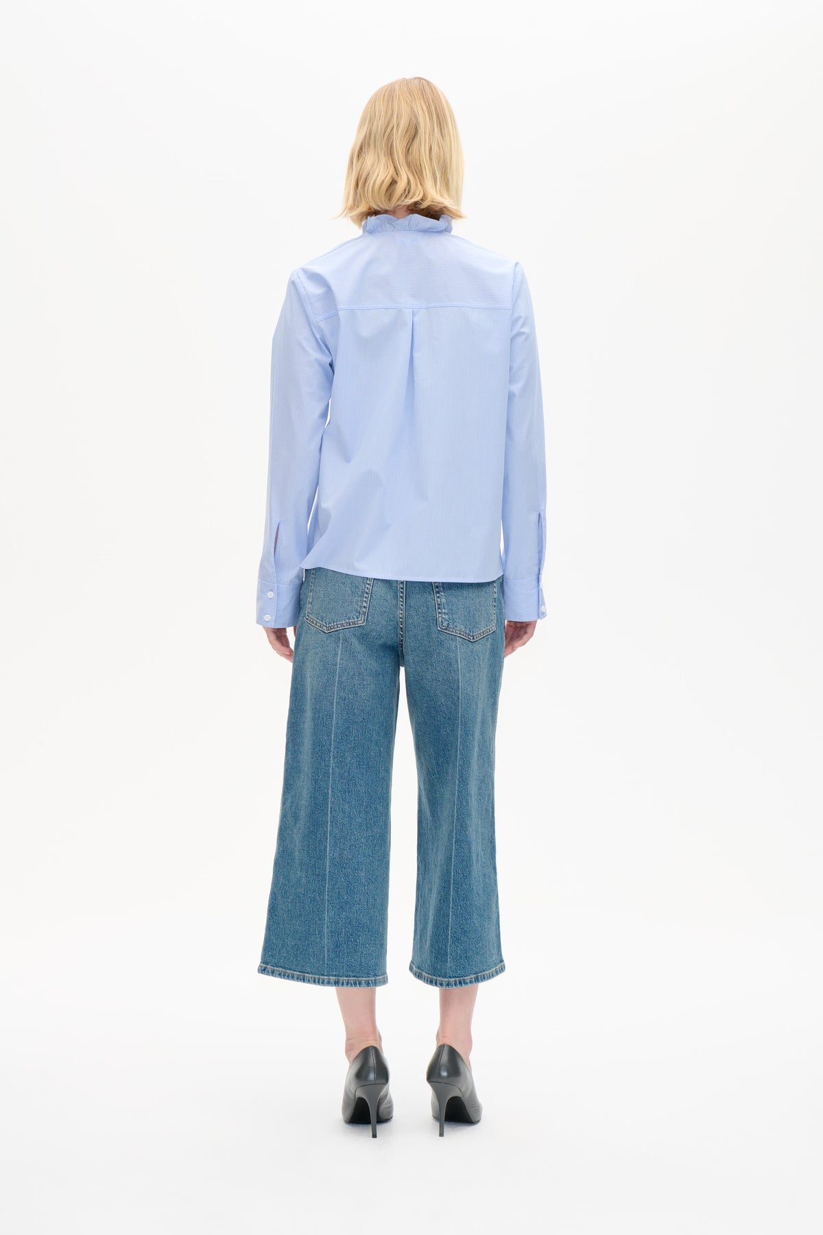 Set bagfra: en lyseblå skjorte i fint tern med flæsekrave og rygplissé, stylet med wide-leg cropped jeans.