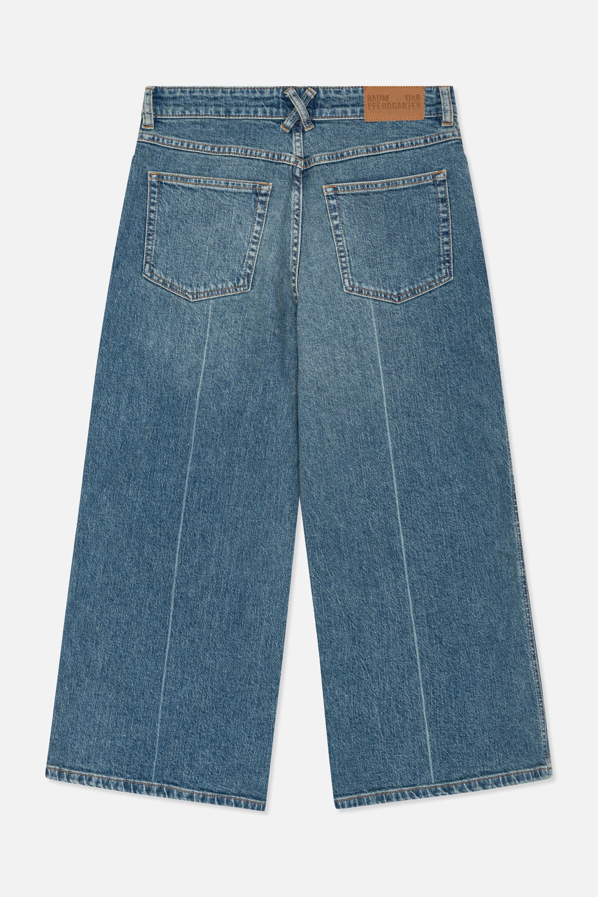 Nærbillede af bagsiden af blåvaskede denimjeans med to påsyede lommer, orange kontrastsyning og et lysebrunt lædermærke i taljen.
