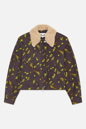 Forfra en mørk koksgrå denimjakke med spredt blomsterprint i gulgrøn og orange, skrå paspolerede lommer og en kraftig, cremet krave med struktur.