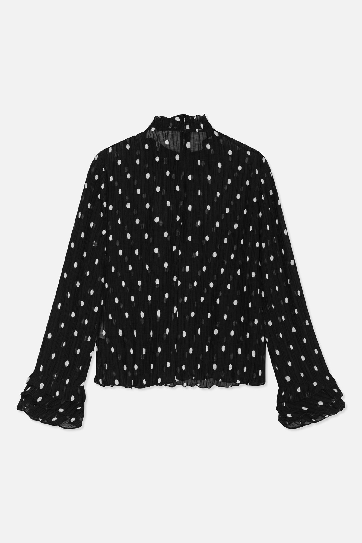 Set bagfra: transparent sort bluse med uregelmæssige hvide prikker, høj hals, lange ærmer og flæsemanchetter.
