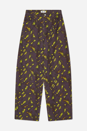 Forfra: wide-leg jeans i mørk blomme med spredt gulgrønt og rustfarvet blomsterprint, buede frontsømme og lommer.